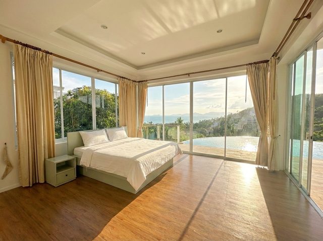 Large double bedroom with panoramic windows overlooking the sea and pool
