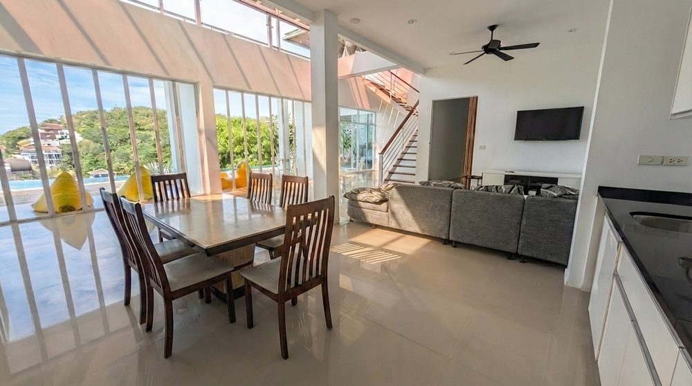 Open-plan living and dining space with pool view and soft seating
